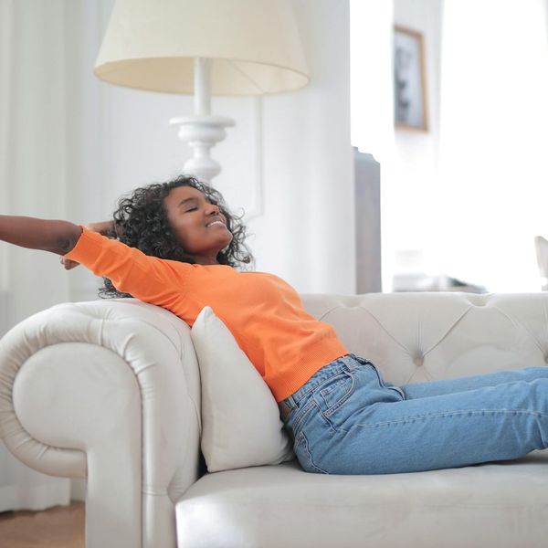 Smiling woman stretching gently in a bright, airy room.